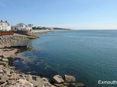 A coastal scene with rocks and seawall along water at Exmouth