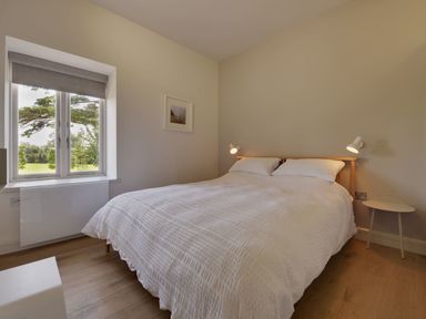 A bedroom with a double bed white bedding two bedside lamps window with view of trees and field at Gardeners Cottage Talaton near Ottery St Mary