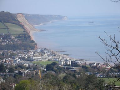 A coastal town with buildings near cliffs and calm sea at Sidmouth in Devon
