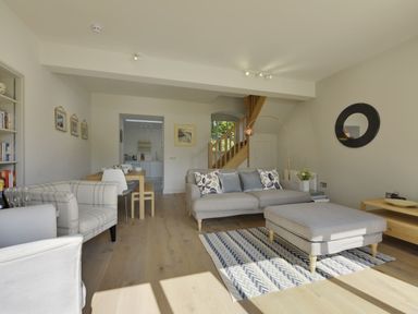 A living room with sofa chairs dining table and staircase at Gardeners Cottage in Talaton near Ottery St Mary