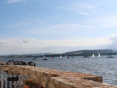 A view of a body of water with sailboats and hills in the background at 1 The Quay in Lympstone