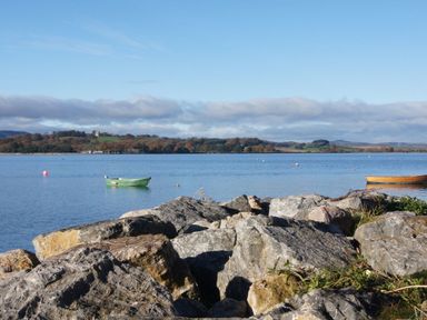 A body of water with two small boats floating and rocks in the foreground at 1 The Quay in Lympstone