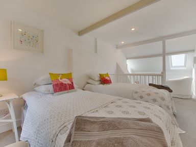 A bedroom with two single beds with patterned bedspreads and decorative pillows at 1 The Quay in Lympstone