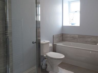 A bathroom with a toilet shower and bathtub near a window at 2 Carlton Mews in Exmouth