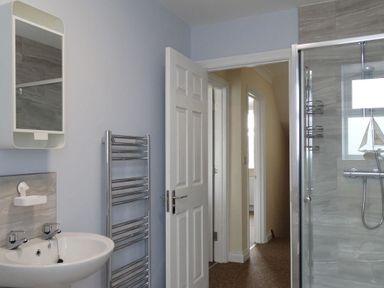 A bathroom with a sink a wall mirror a heated towel rail and a glass shower enclosure at 2 Carlton Mews in Exmouth