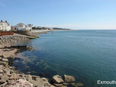 A coastal view with rocky shoreline and buildings along the edge at 2 Carlton Mews in Exmouth