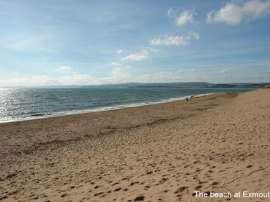 A sandy beach with the sea on the left and hills in the background at 2 Carlton Mews in Exmouth