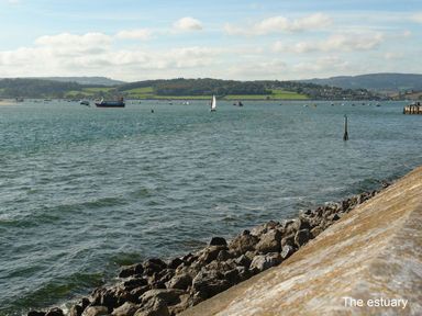 A rocky shoreline with boats on water and hills in the background at 2 Carlton Mews in Exmouth