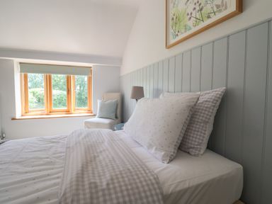A bedroom with a bed and window at The Old Log Shed in Honiton