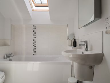 A bathroom with a bathtub, toilet, and sink at The Old Log Shed in Honiton