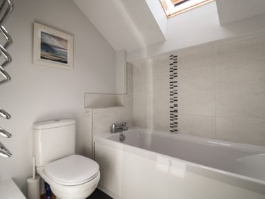A bathroom with a bathtub and toilet at The Old Log Shed in Honiton
