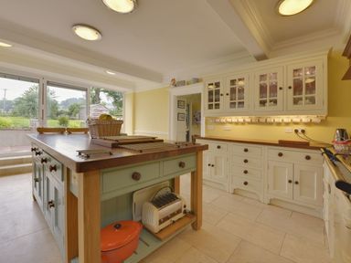 A kitchen with an island and cabinets with glass doors at Abbots Manor Combe Raleigh near Honiton