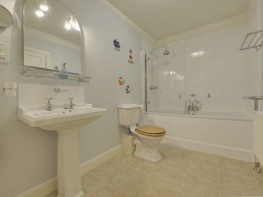 A bathroom with a pedestal sink toilet with wooden seat and a bathtub with shower at Abbots Manor in Combe Raleigh near Honiton