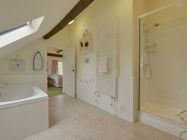 A bathroom with a bathtub skylight towel rack and a shower at Abbots Manor in Combe Raleigh near Honiton