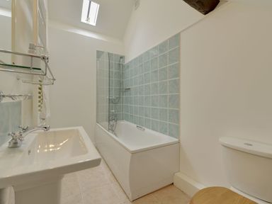 A bathroom with a bathtub with tiled wall and a shower screen a sink and a toilet at Abbots Manor Combe Raleigh near Honiton