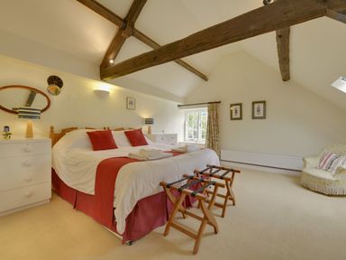 A bedroom with a double bed red pillows and duvet at Abbots Manor in Combe Raleigh near Honiton