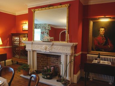 A dining room with a white ornate fireplace and a large mirror above it at Abbots Manor Combe Raleigh near Honiton