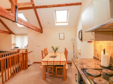 A kitchen dining area with wooden beams skylights and a table with a checkered tablecloth at The Old Stable in Sidbury near Sidmouth