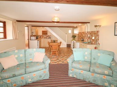 A living area with two sofas and a kitchen with dining table and chairs at The Linney in Colyton