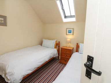 A bedroom with two single beds a wooden nightstand and a skylight window at The Linney in Colyton