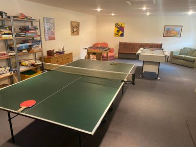 A game room with a ping pong table a foosball table a pool table and shelves with board games at The Linney in Colyton