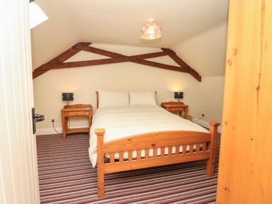 A bedroom with a wooden bed and two bedside tables with lamps at Battens in Colyton
