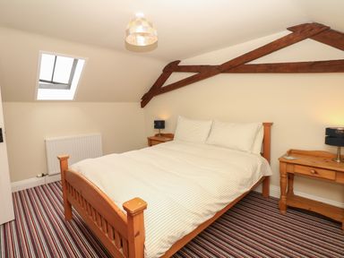 A bedroom with a wooden bed and striped carpet at Battens in Colyton
