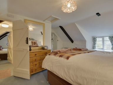 A bedroom with a bed towels on it a wooden chest of drawers and a mirror at Lew Quarry Cottage Lewdown