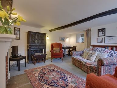 A living room with a patterned sofa armchair carpet and wooden furniture at Lew Quarry Cottage in Lewdown