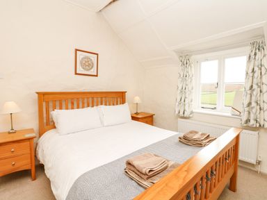 A bedroom with a wooden bed and two bedside tables with lamps at West Henstill House in Sandford Devon