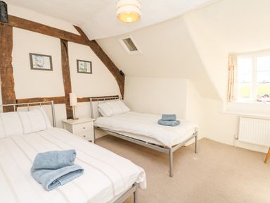 A bedroom with two single beds next to a window and wooden beams on the wall at West Henstill House in Sandford Devon