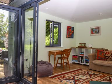 A snug with a table, chair, and bookshelf at Hope Cottage in Riddlecombe, near Winkleigh