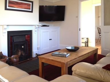 A living room with a fireplace television on cabinet wooden coffee table and leather sofas at Hedgelea in North Tawton
