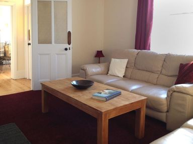 A living room with a wooden coffee table a leather sofa and a lamp at Hedgelea in North Tawton