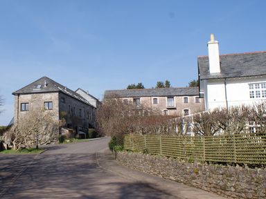 A road with stone buildings and a white house with a chimney at Linney Cottage in Dittisham