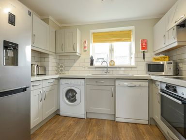 A kitchen with appliances including a refrigerator washing machine dishwasher microwave and oven at Linney Cottage in Dittisham