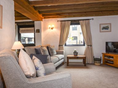 A living room with sofas a wooden coffee table and a television at Bramble Cottage in Ringmore