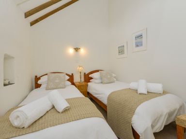 A bedroom with two single beds side by side with a nightstand and lamp between them at Bramble Cottage in Ringmore