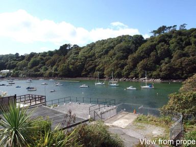 A waterfront view with boats anchored in the water and wooded hills in the background at Galanda Treetops in Newton Ferrers