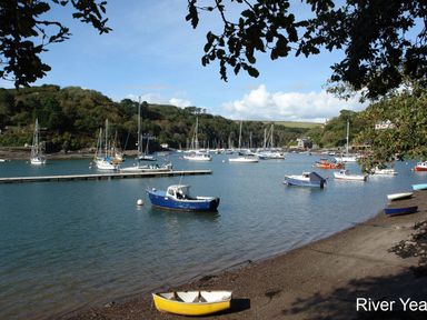 A river with boats anchored and trees on the shoreline at Galanda Treetops in Newton Ferrers