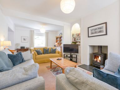 A living room with sofas a wooden coffee table a fireplace and a television at 4 Coastguards Cottage in Hope Cove