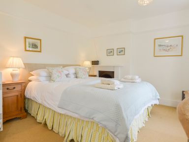 A bedroom with a double bed bedside tables lamps and framed pictures at 4 Coastguards Cottage in Hope Cove
