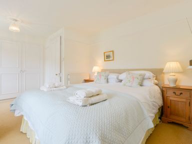 A bedroom with a large bed with folded towels on top and nightstands with lamps at 4 Coastguards Cottage in Hope Cove