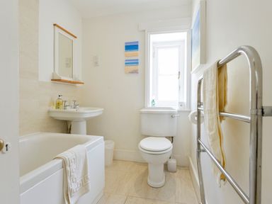 A bathroom with a bathtub sink toilet and towel rack at 4 Coastguards Cottage in Hope Cove
