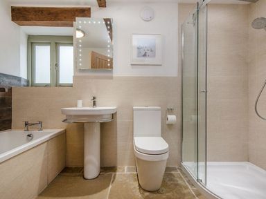 A bathroom with a bathtub sink toilet and glass shower enclosure at Mill Barn in Woolston near Salcombe