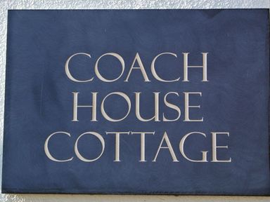 A blue sign with the words Coach House Cottage