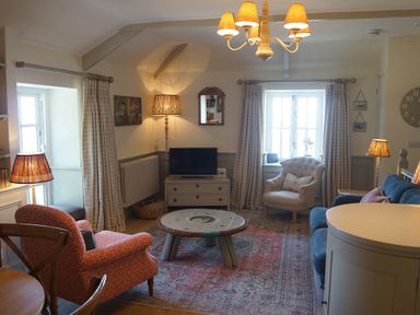 A living room with a sofa, armchair, and coffee table at Coach House Cottage, Strete, near Dartmouth