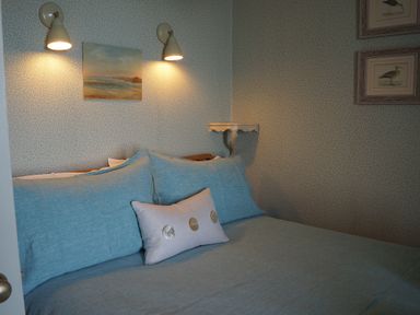 A bedroom with a bed and wall art at Coach House Cottage in Strete, near Dartmouth