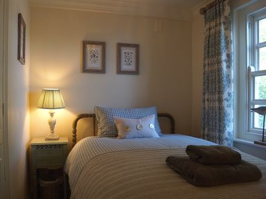 A bedroom with a bed and lamp at Coach House Cottage, Strete, near Dartmouth