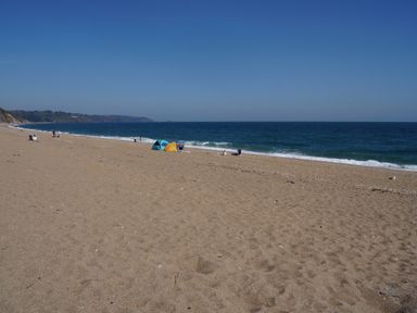 A beach with people and tents at Coach House Cottage in Strete, near Dartmouth
